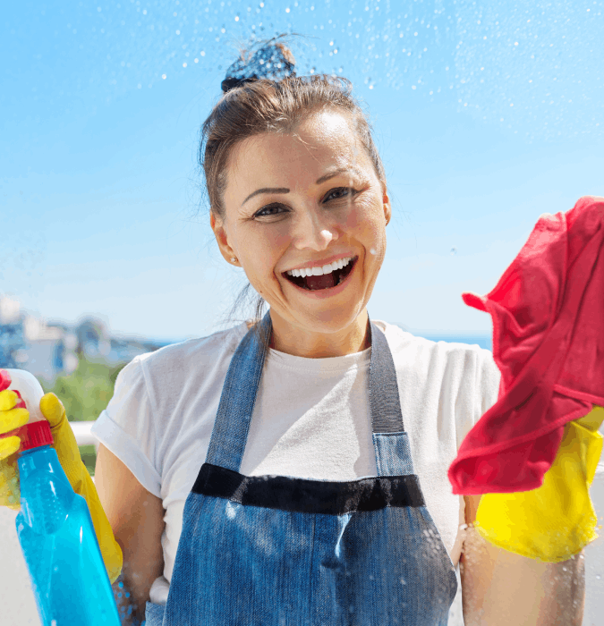 Smiling woman cleaning window with spray bottle and cloth. Professional window cleaning service concept. House cleaning, housework.